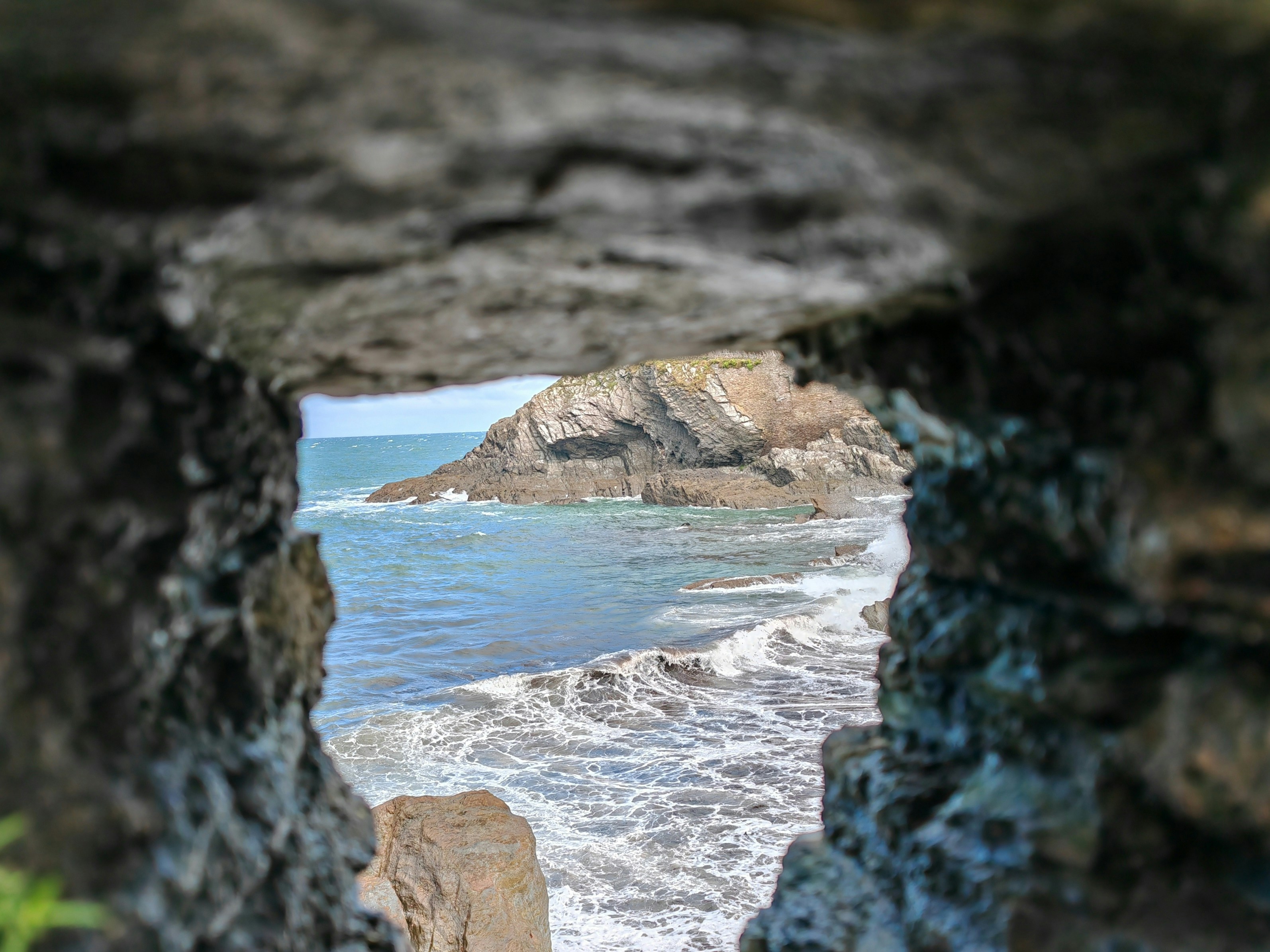 a view of the ocean through a hole in a rock, 