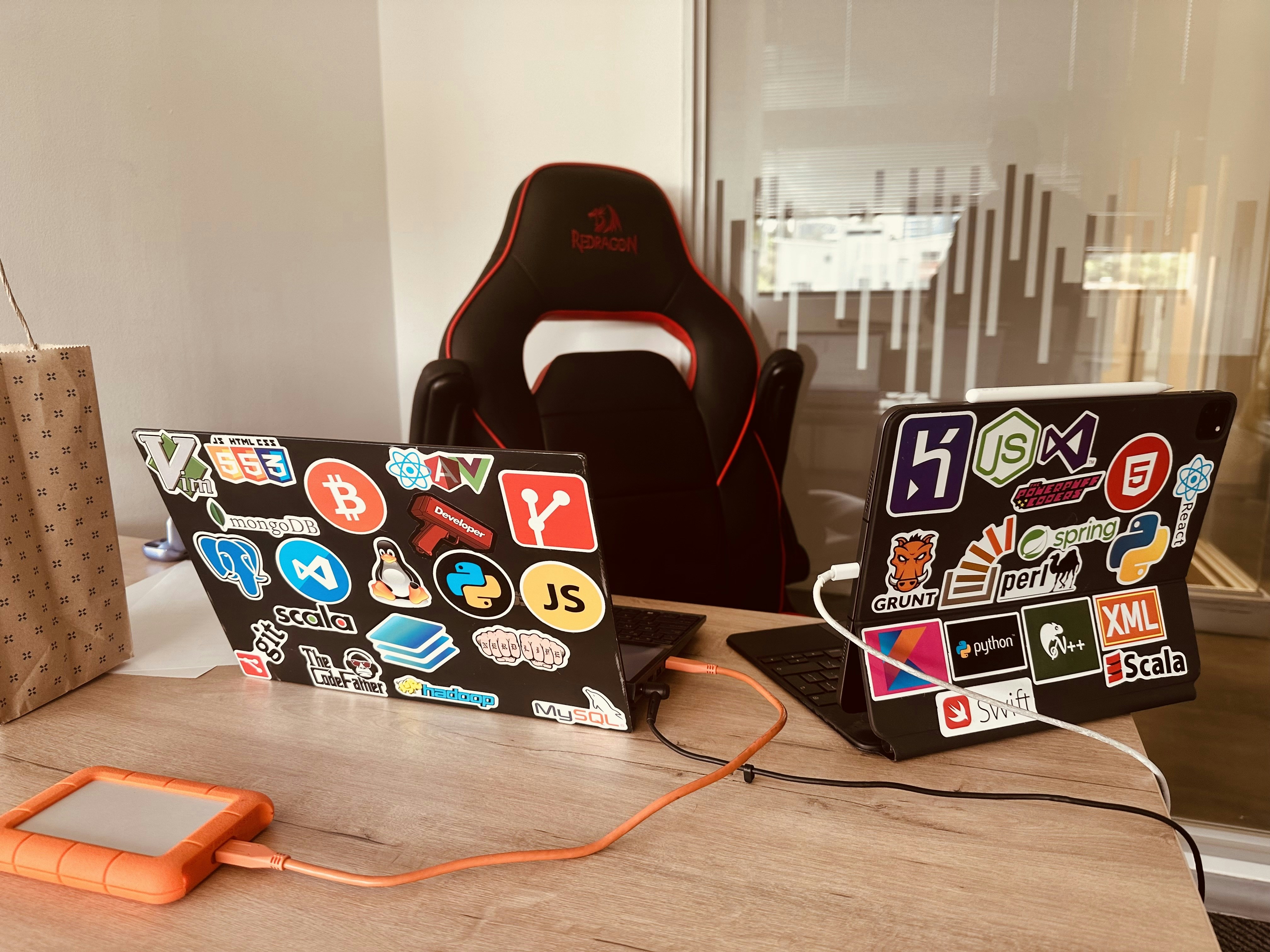 Laptop covered in colorful holographic stickers with cyber and gaming aesthetic on dark wooden desk