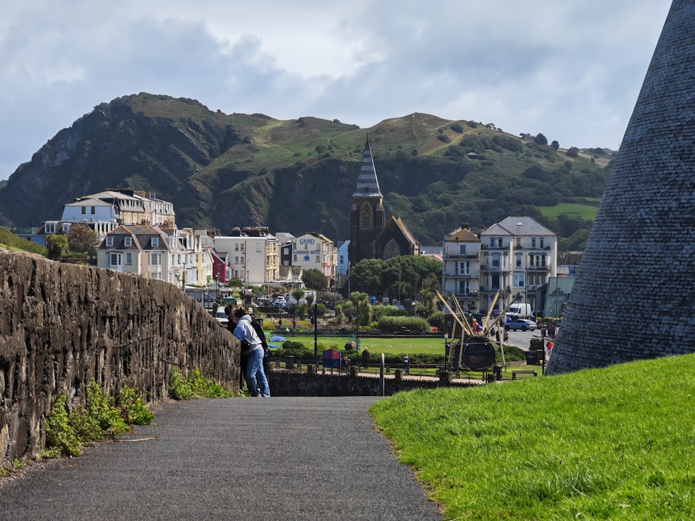 a couple of people standing next to a stone wall