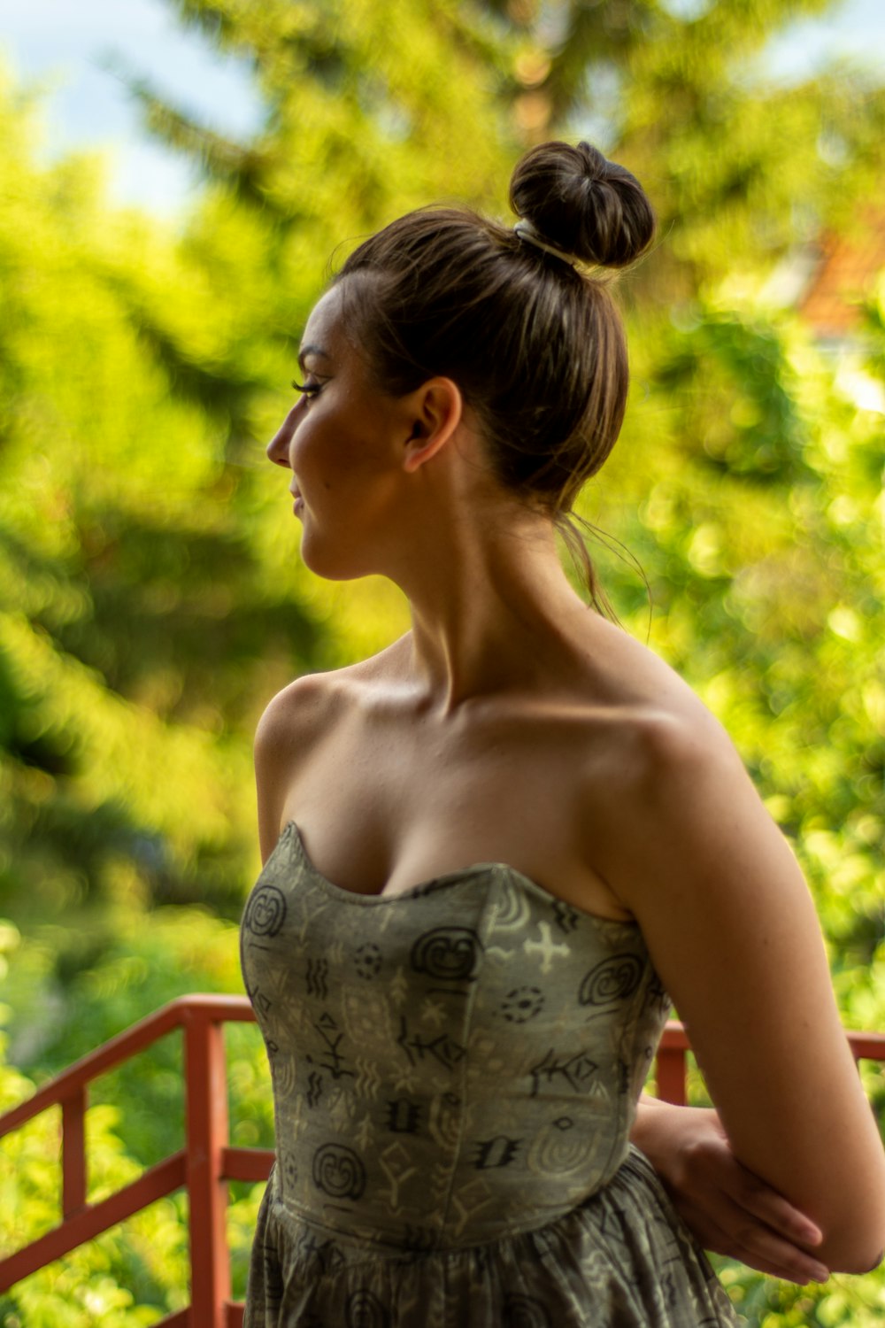 a woman in a strapless dress standing on a balcony