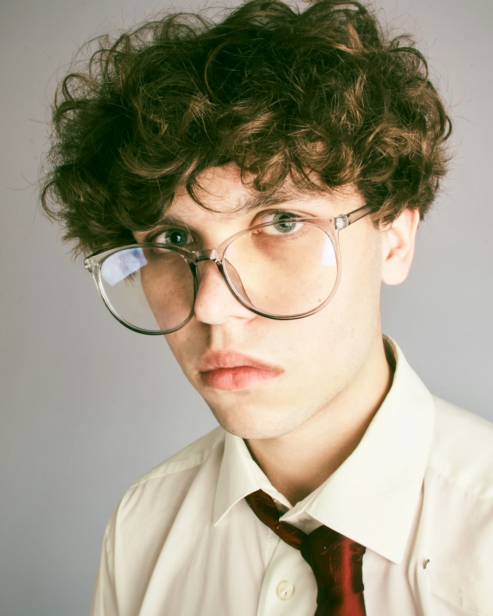 a young man wearing glasses and a tie