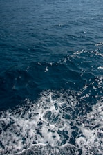 a boat in the ocean with the wake of the boat