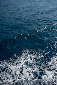 a boat in the ocean with the wake of the boat