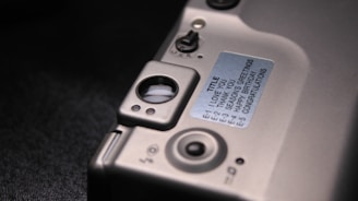 A close-up view of a section of an electronic device featuring a metallic surface with buttons and switches. A label is affixed to the surface, containing text for different greetings or messages. The layout suggests a customizable electronic message feature.