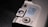 A close-up view of a section of an electronic device featuring a metallic surface with buttons and switches. A label is affixed to the surface, containing text for different greetings or messages. The layout suggests a customizable electronic message feature.