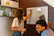 A smiling tutor explaining a concept to a student using a whiteboard in a modern classroom.