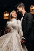 A joyful couple holding hands, smiling warmly at the camera during their wedding photoshoot.