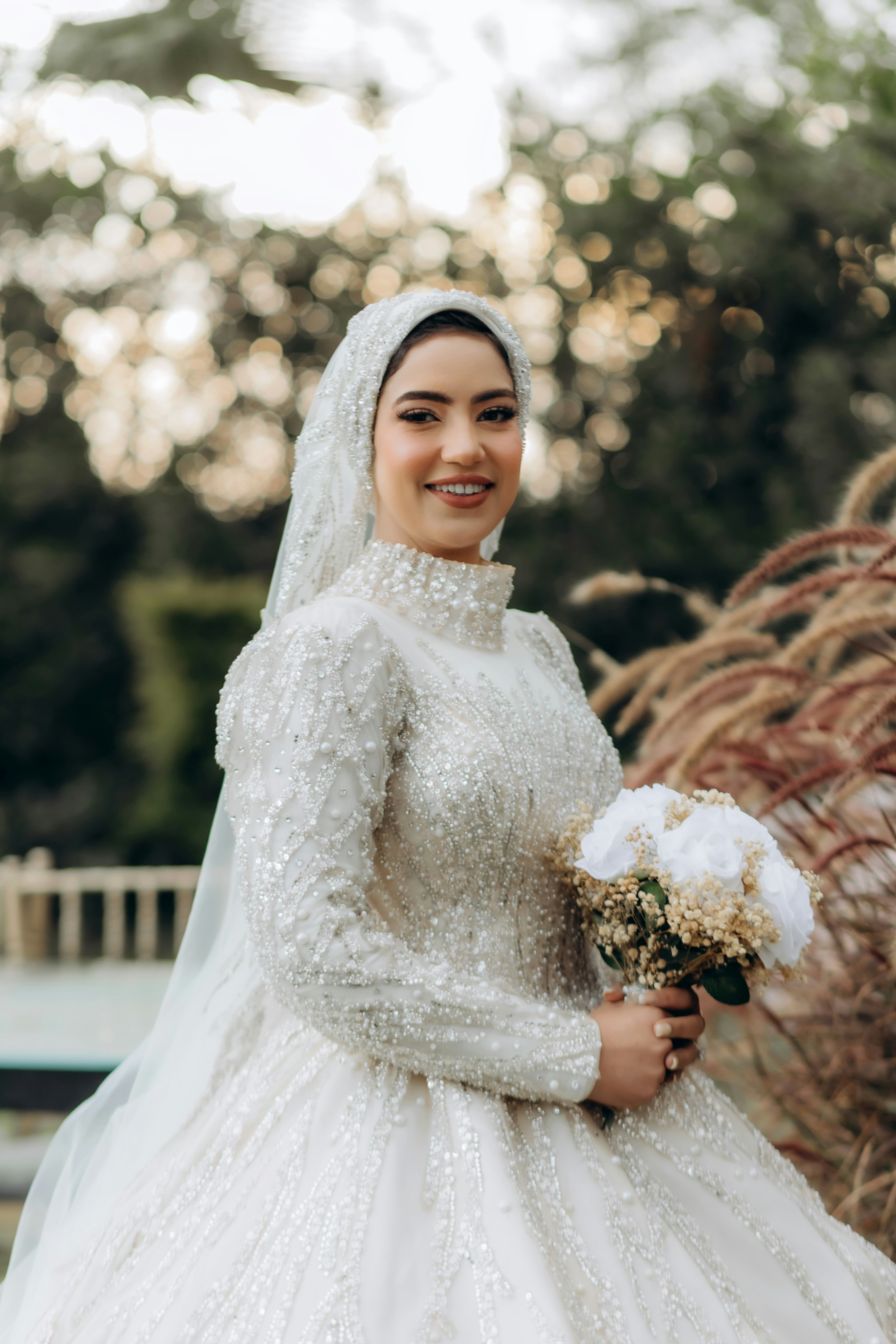 Mariée algérienne en robe blanche tenant un bouquet de roses, lumière dorée naturelle