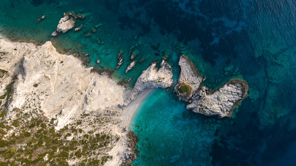 an aerial view of a rocky coastline with clear blue water