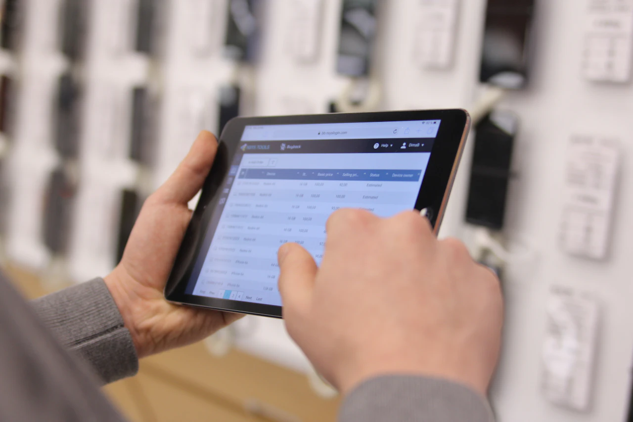 A staff member reading a table of product figures on a tablet on the retail floor, the transaction detail every report is built from