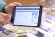 Close-up of hands managing cash and credit sales on a tablet
