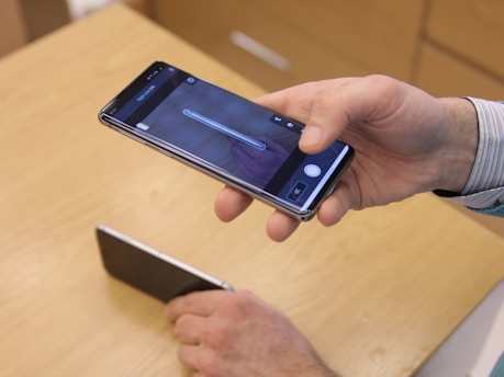 A smartphone screen showing photos being transferred from an iPhone to an Android device.