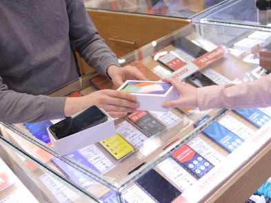 a man and a woman exchanging a cell phone at a store