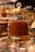 A glass jar with a gold-colored lid filled with a large quantity of saffron strands. The jar is elegantly designed with decorative elements and a crystal-like handle on top. It is placed on a glass shelf surrounded by other spice containers and small boxes.