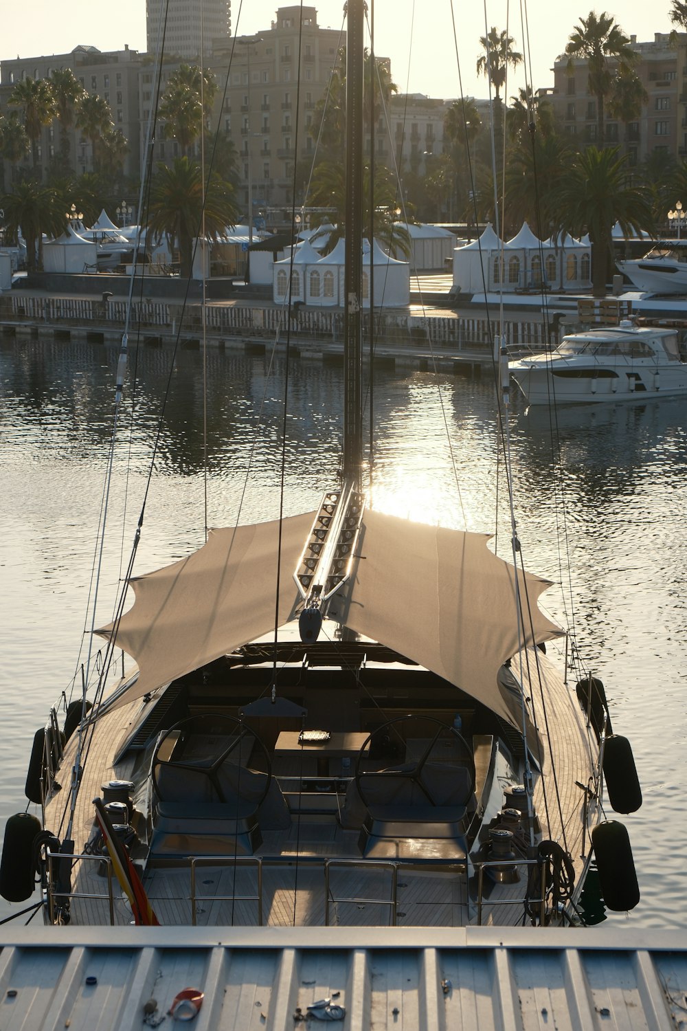 a sailboat docked in a harbor with palm trees in the background