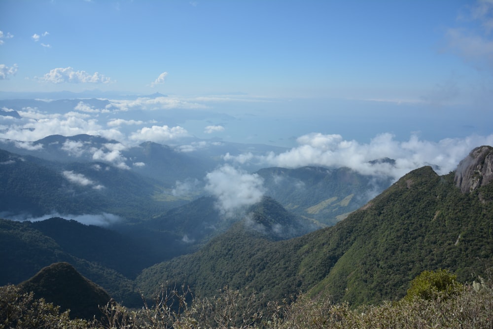 a view of the mountains and clouds from the top of a hill