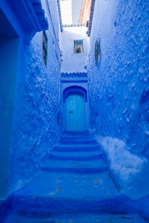 a narrow alley with blue walls and steps