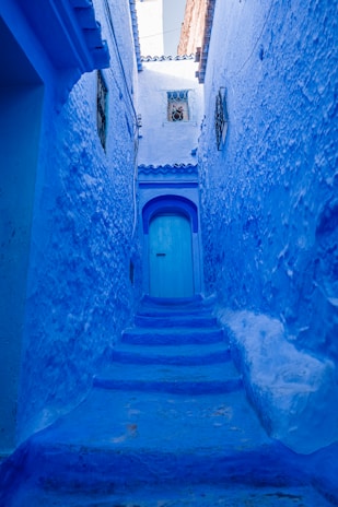 a narrow alley with blue walls and steps