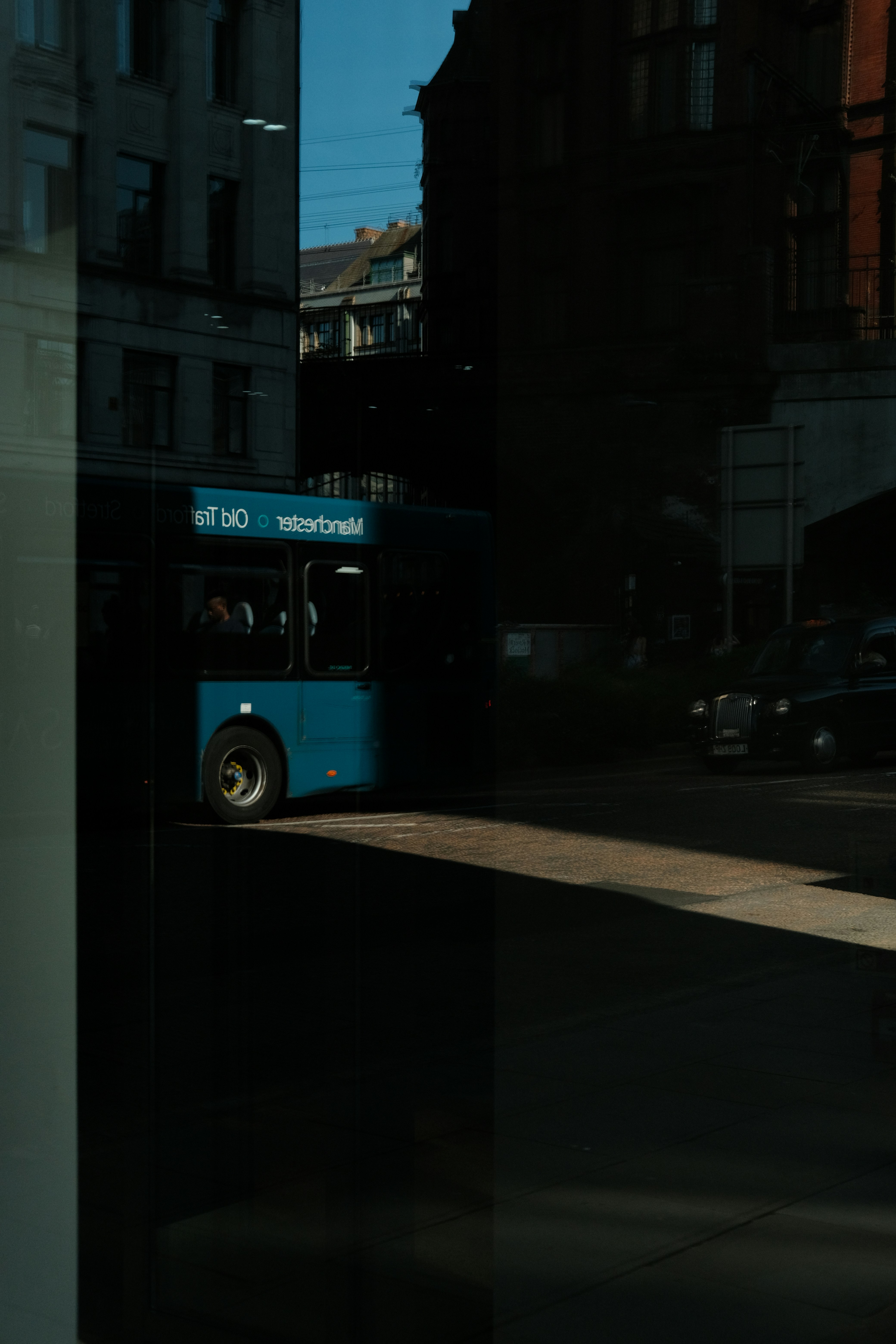 a blue bus driving down a street next to tall buildings
