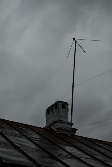Close-up of a lightning rod installed on a rooftop with stormy clouds in the background