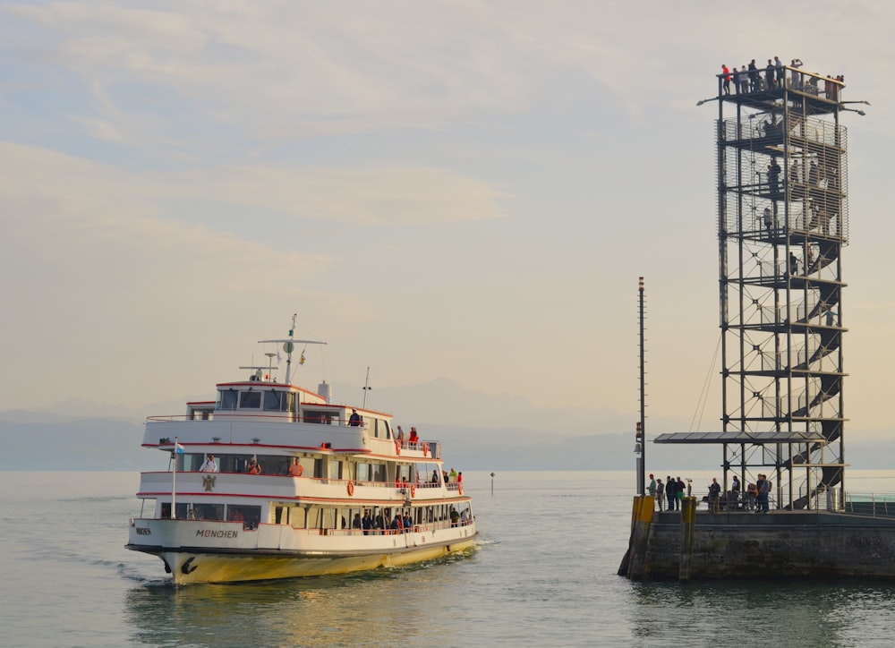 a large boat is in the water next to a tower