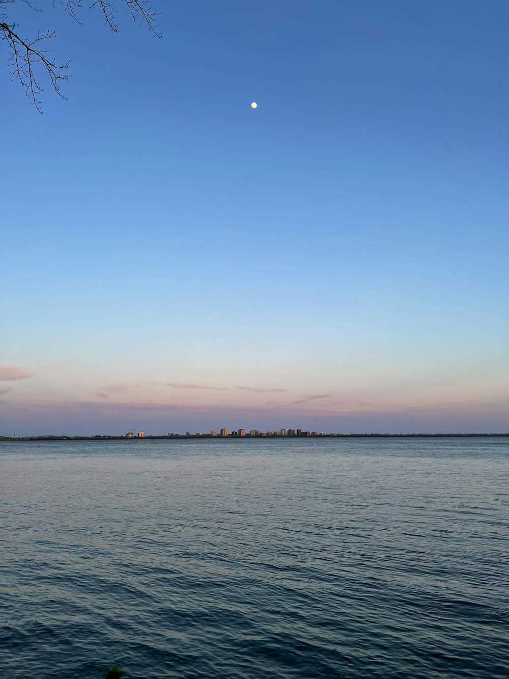 a large body of water with a moon in the sky