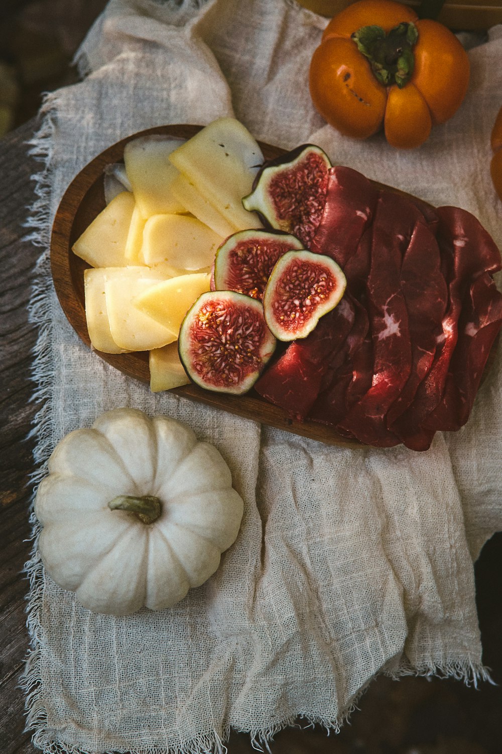 a plate of meat, cheese, and fruit on a table