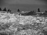 Waves captured in motion with a focus on the texture and details of the water. In the background, silhouettes of people stand out against the horizon, giving the scene a dramatic and mysterious feel.