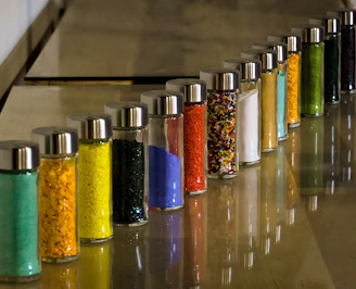 Close-up of colorful chemical powders in small containers on a lab bench