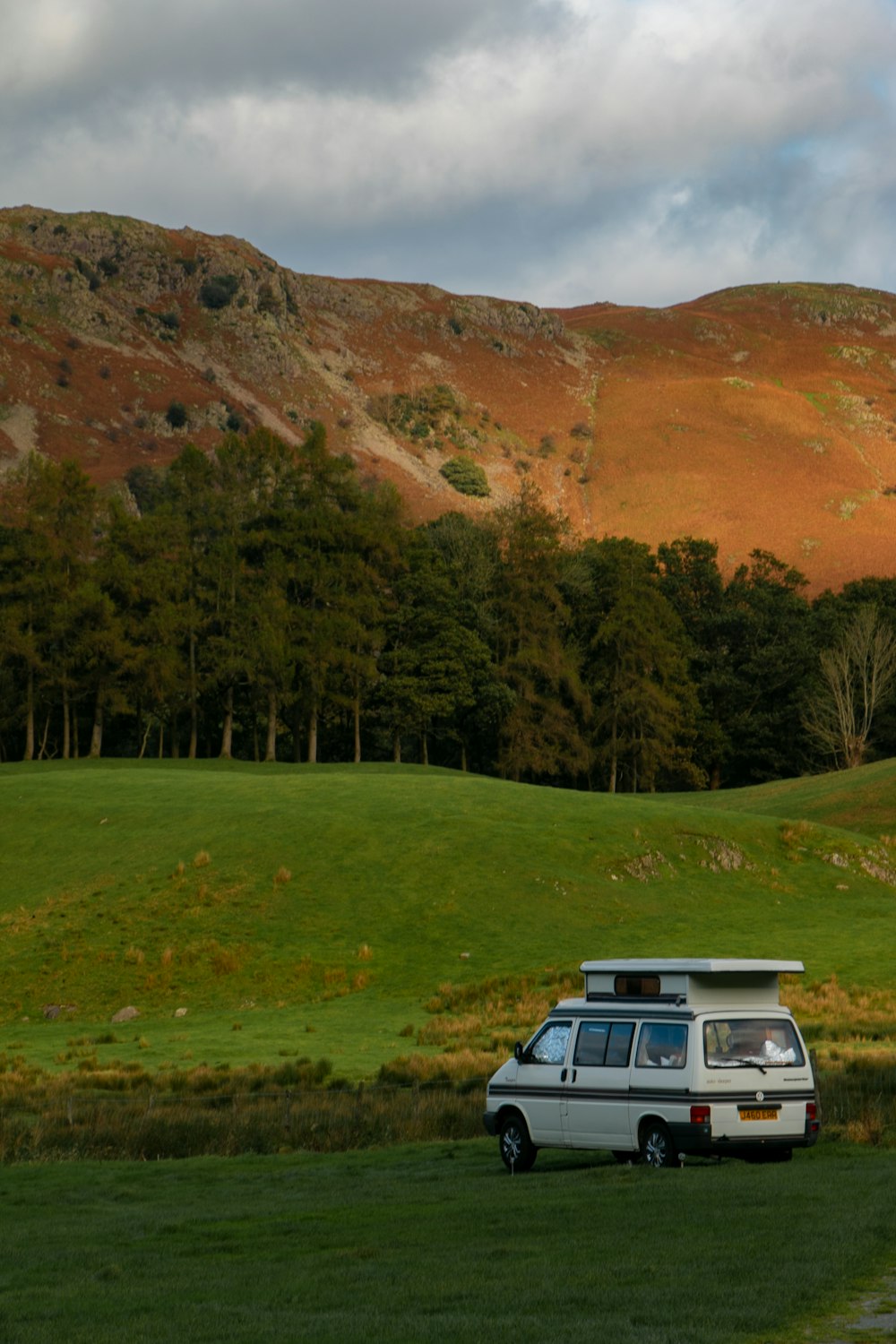 a van parked in a field with mountains in the background