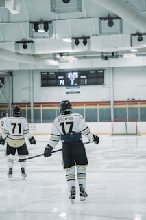 Two hockey players are on an ice rink, one with the name 'Spadafora' and number 17 on their jersey, and another with number 71. The score displayed on the scoreboard is Home 14, Guest 1, with the period indicated as 3 and the remaining time as 18:25.