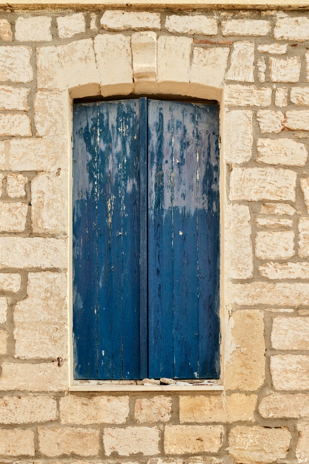 a window with blue shutters on a stone building