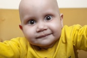 Close-up of a smiling baby surrounded by soft natural light in a studio setting.