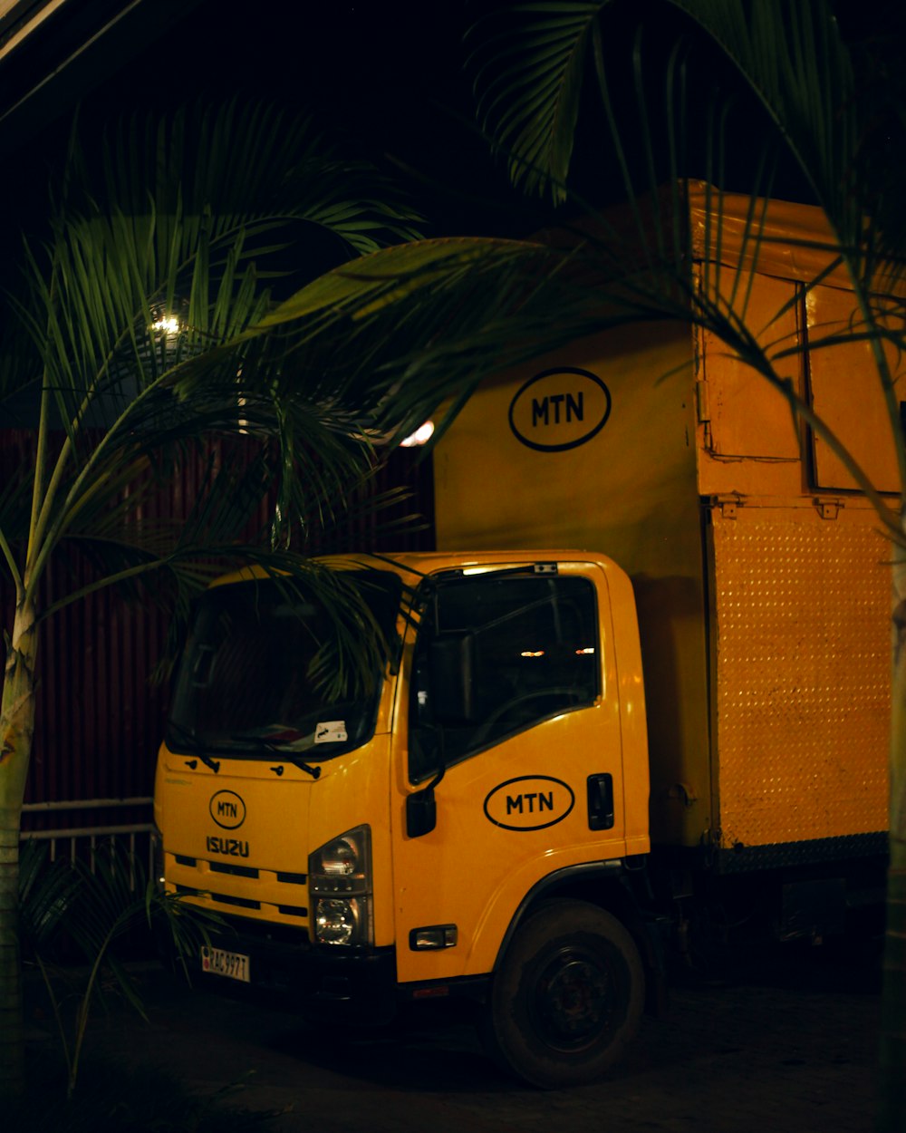 a yellow truck parked next to a palm tree