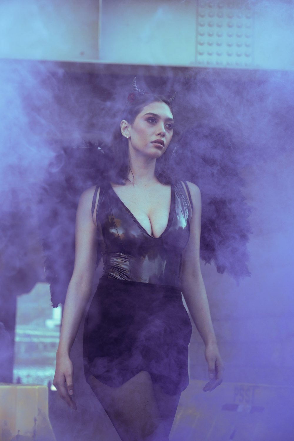 a woman in a black dress standing in smoke