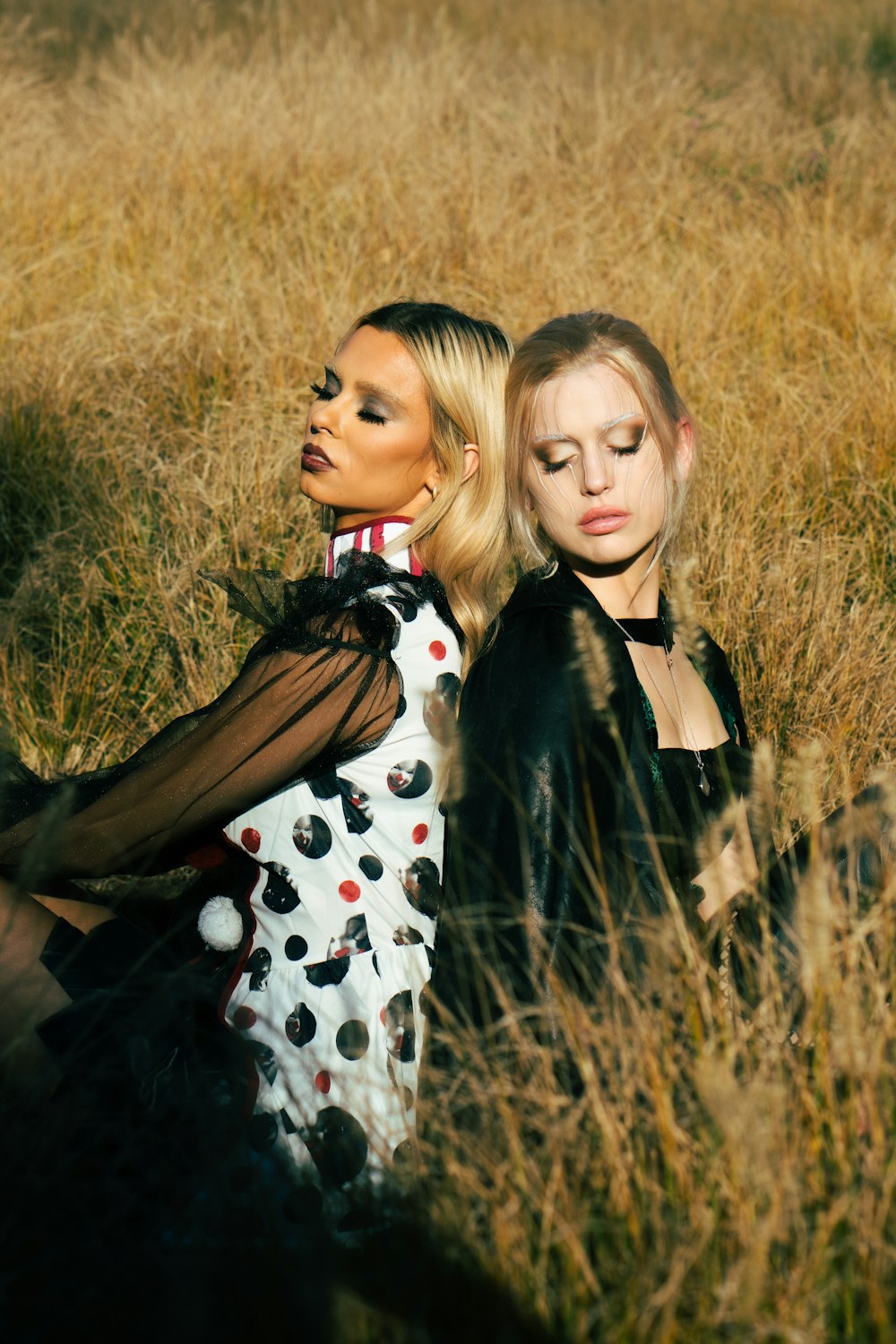 two women sitting in a field of tall grass