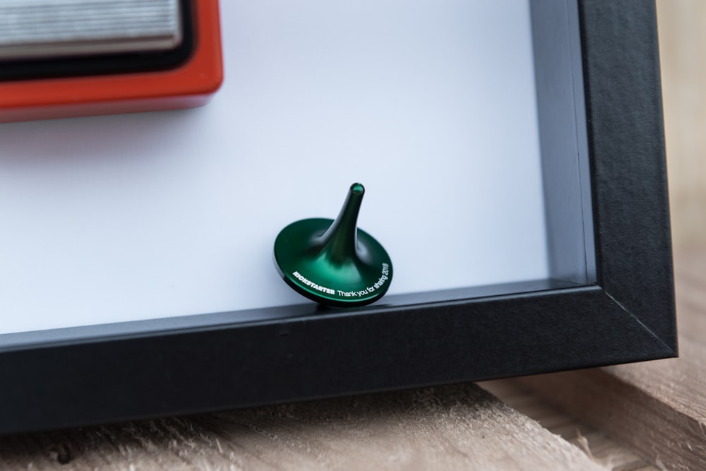 a small green object sitting in a shadow box