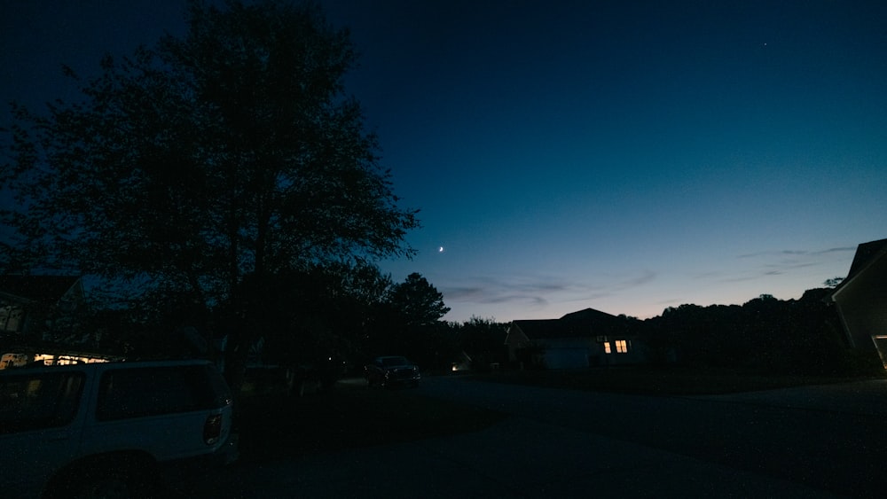 a dark street at night with a car parked on the side of the road