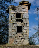 a stone tower sitting on top of a grass covered hillside