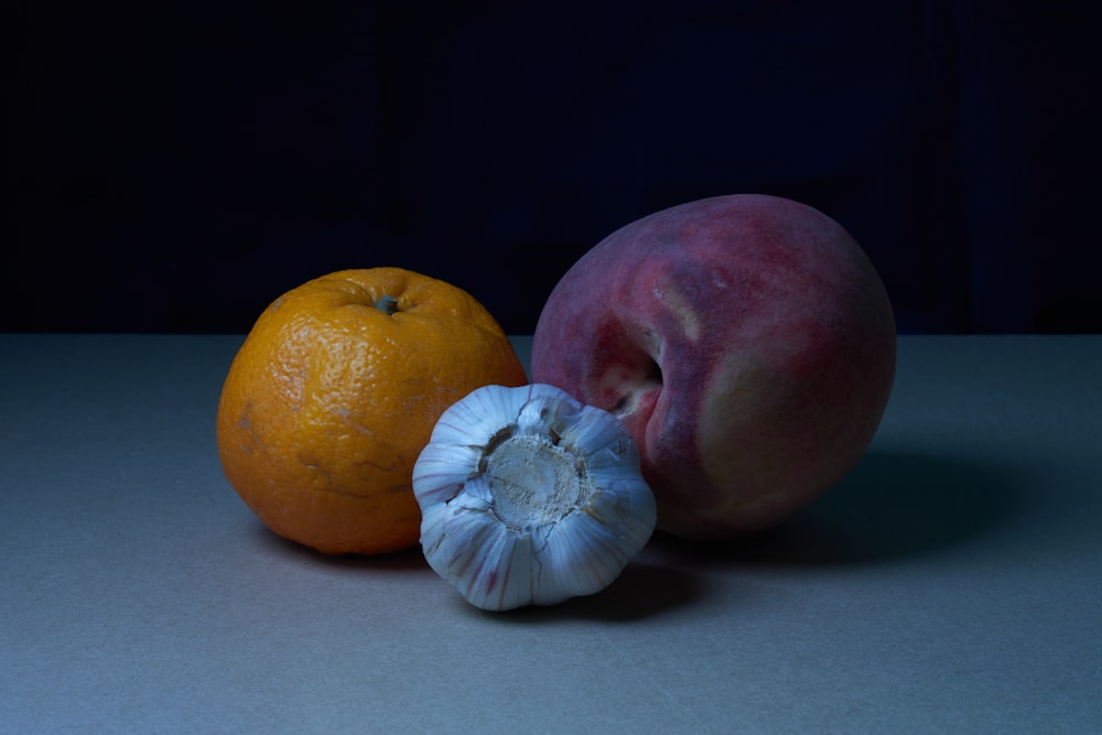 an orange, an apple and an onion on a table