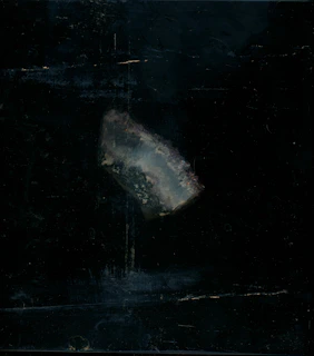 Steel-grey tungsten mineral texture with fine crystalline structure illuminated against a dark backdrop