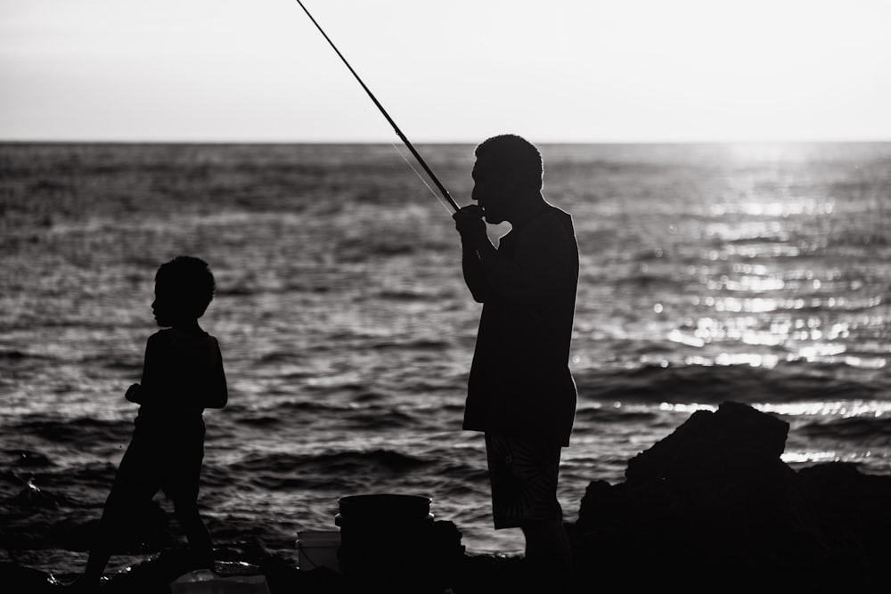 a black and white photo of a man and a child fishing