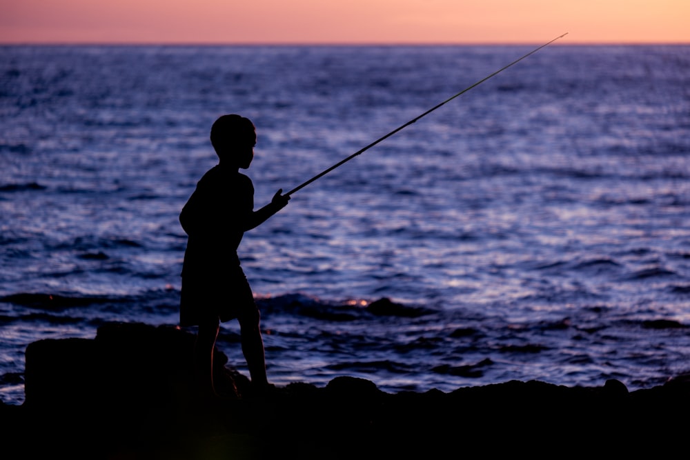 a man standing on top of a rock next to the ocean