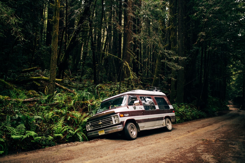 a van is parked on a dirt road in the woods