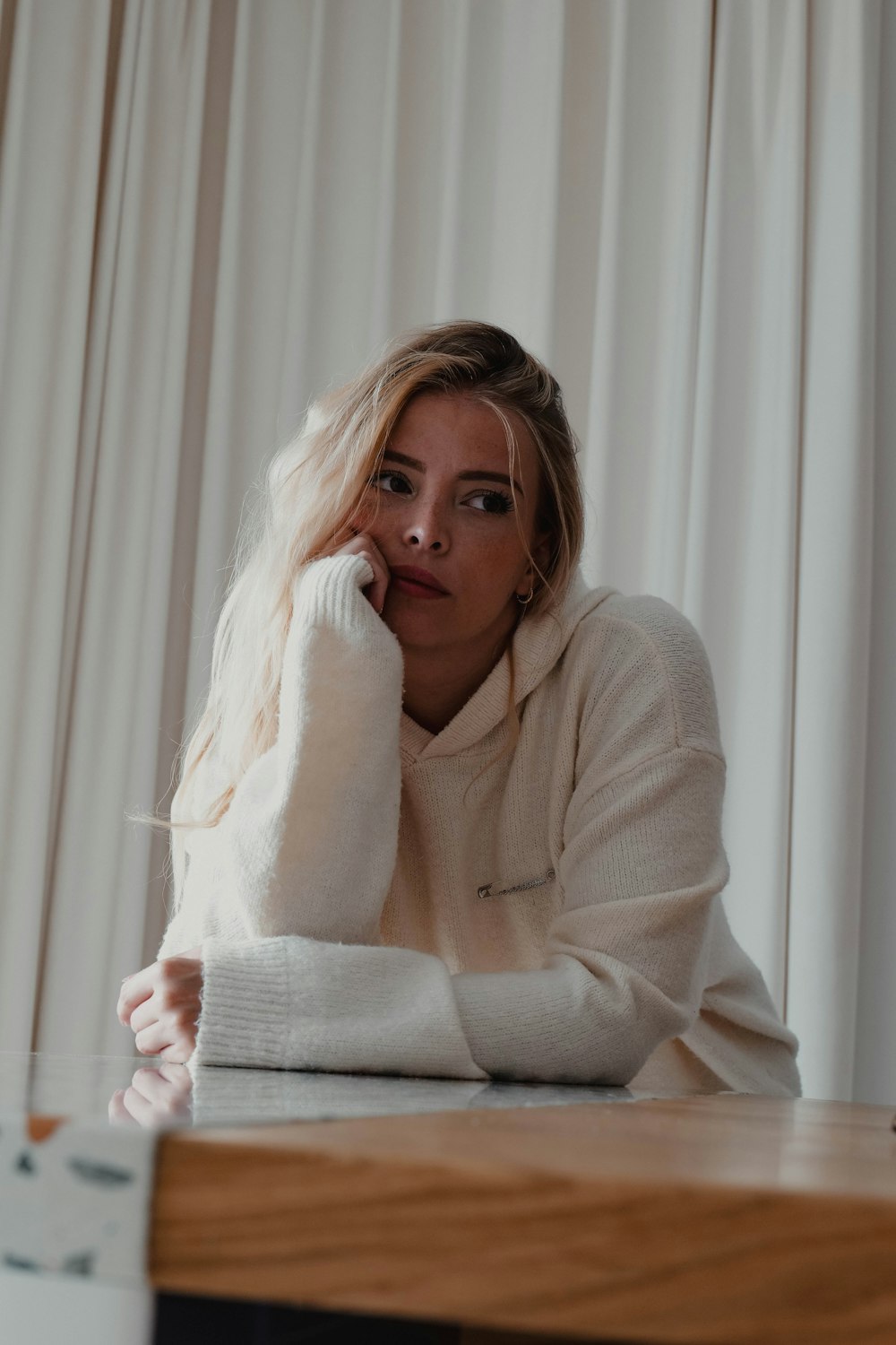 a woman sitting at a table with her hand on her face