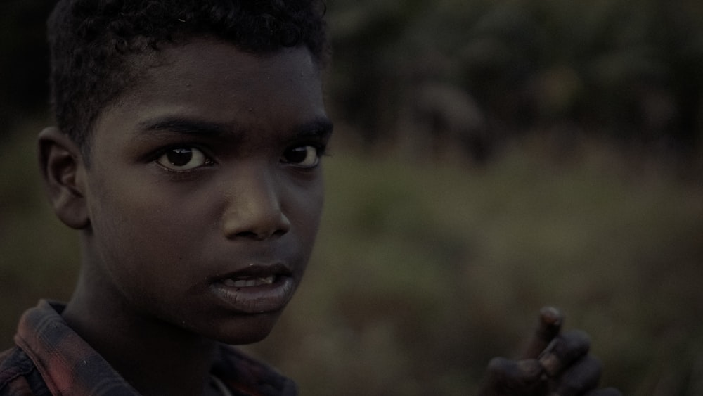 a close up of a young person holding a cigarette