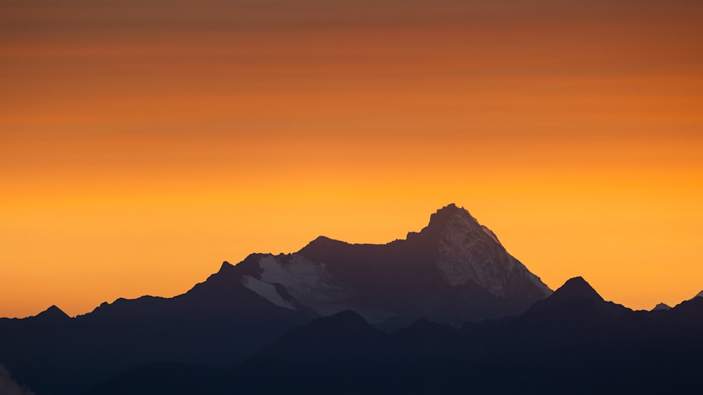 the sun is setting behind a mountain range