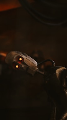A metallic robot with glowing red eyes and a slightly tilted head appears against a dark background. The robot's joints and mechanical components are visible, emphasizing its futuristic design.