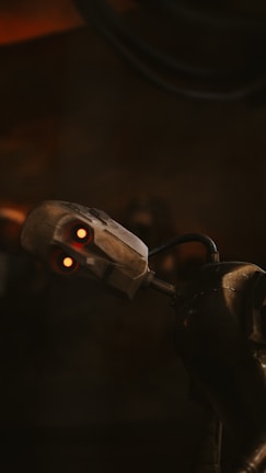 A metallic robot with glowing red eyes and a slightly tilted head appears against a dark background. The robot's joints and mechanical components are visible, emphasizing its futuristic design.