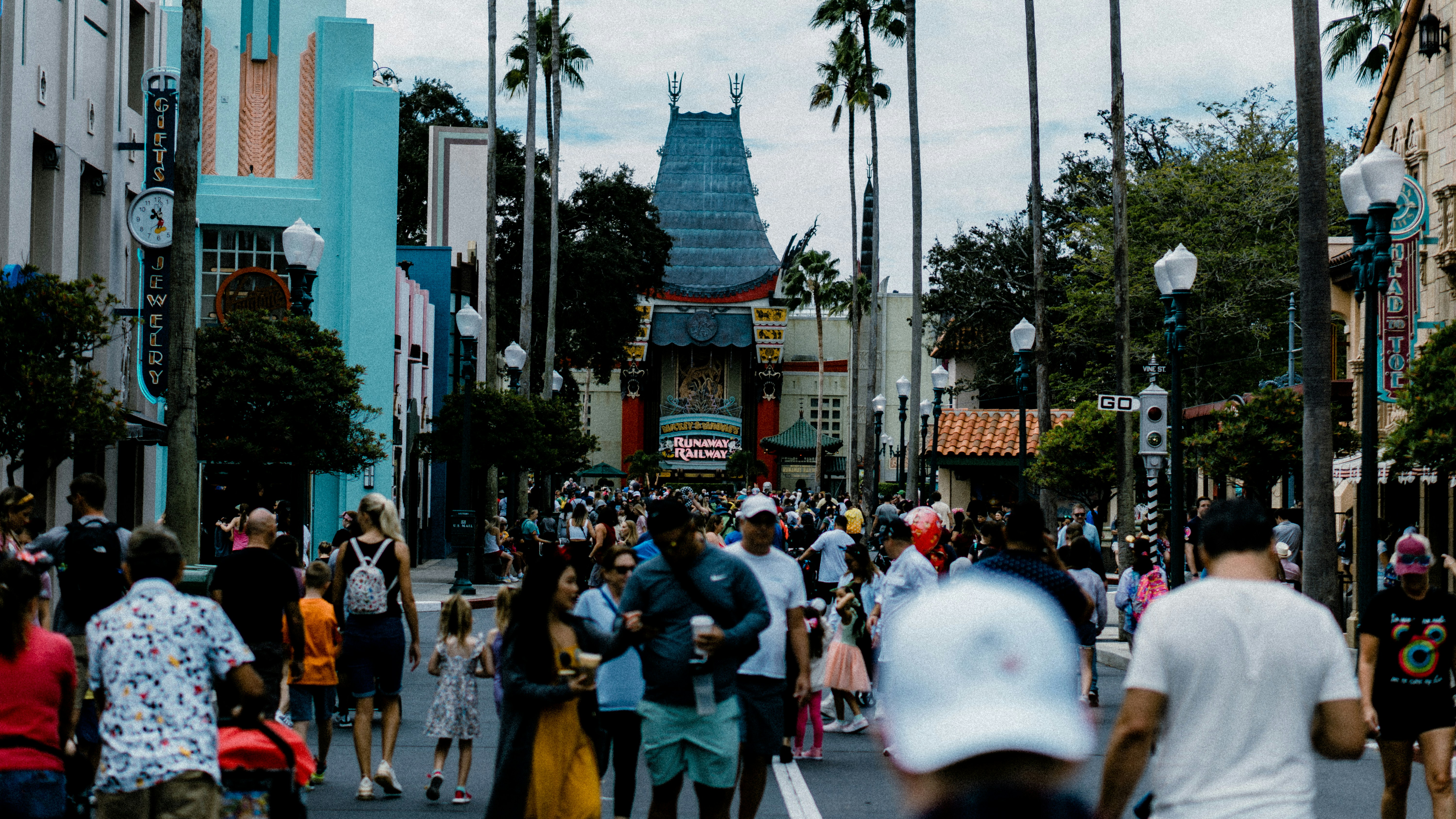 a crowd of people walking down a street next to tall buildings